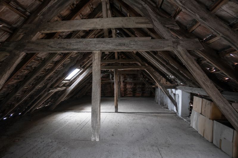 Nicht ausgebauter Dachstuhl mit alten Sparren und Pfetten, Tageslicht fällt durch ein Dachfenster