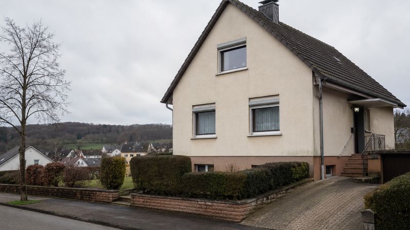 Freistehendes Einfamilienhaus mit hellem Putz und dunklem Satteldach an einer Straße im Saarland
